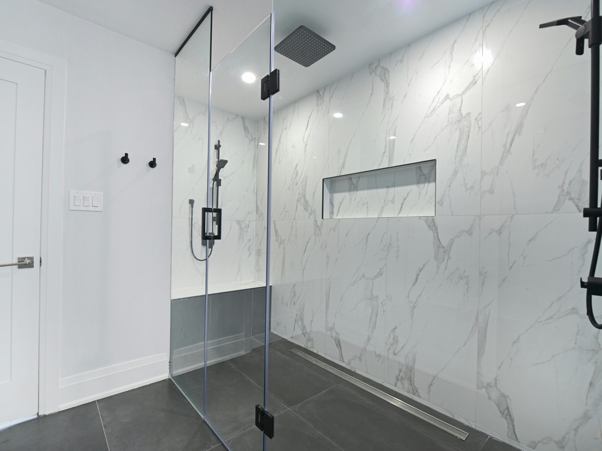 Representative finished bathroom with marble effect tiling and frameless glass shower